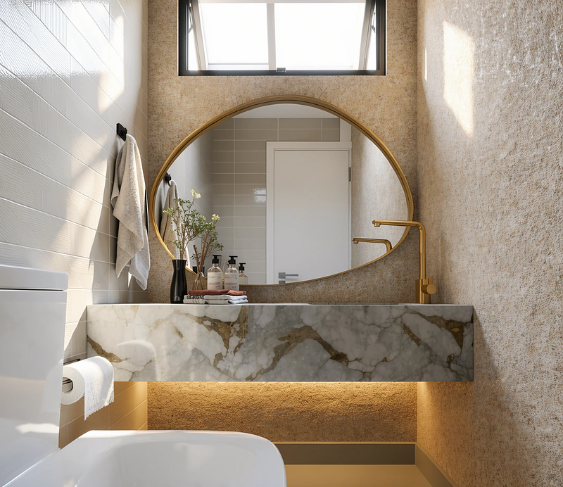 Banheiro com bancada em mármore, espelho oval dourado e nicho iluminado